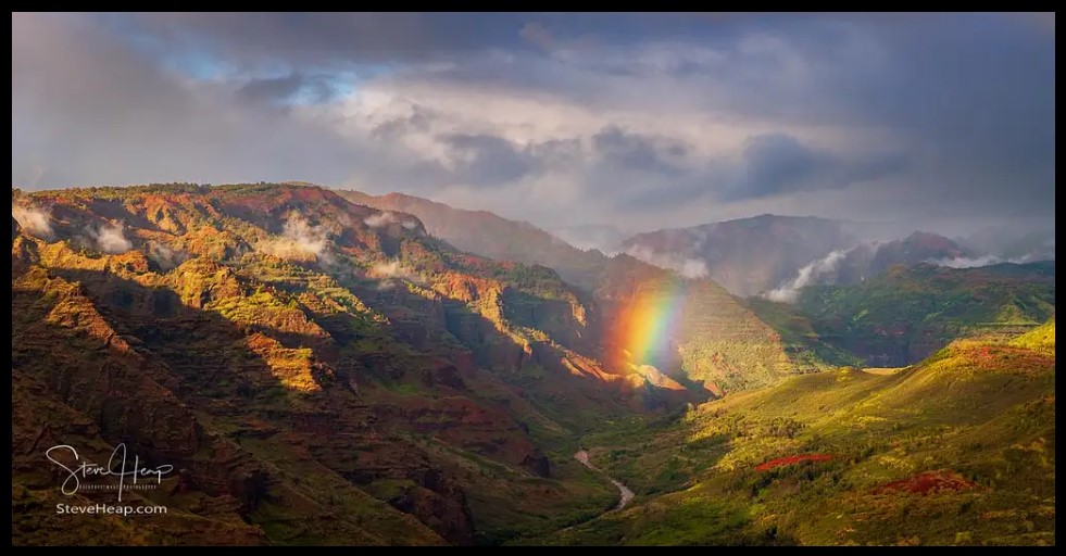 a rainbow adds a splash of spectacular color to this photo of Waimea Canyon on Kauai in Hawaii